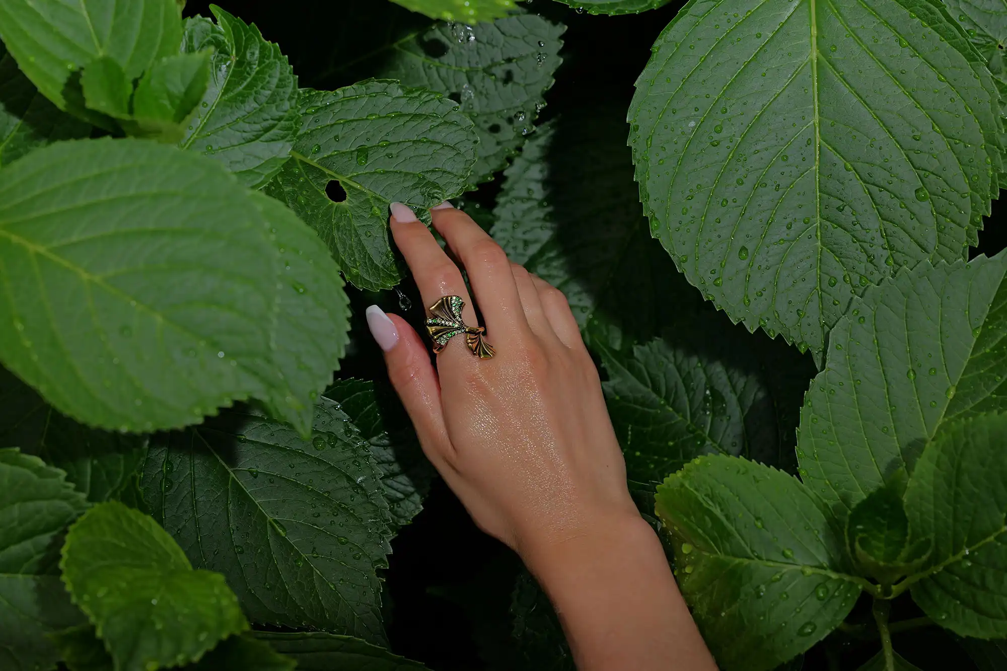 Mano curata di ragazza immersa nelle foglie che mostra un anello posizionato nell'indice
